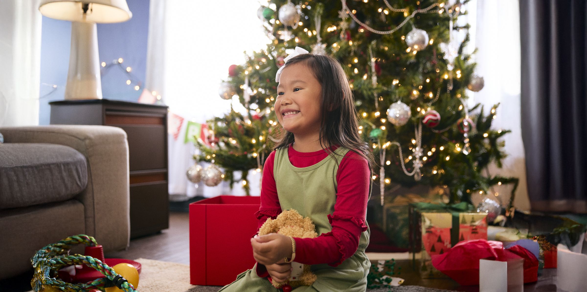 Smiling girl in front of a lit Christmas tree