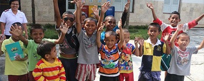Children cheering with a Salvation Army officer in the background.